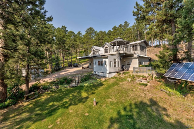 back of property with a lawn, a gazebo, and solar panels