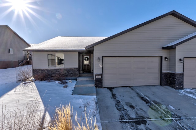 view of front of home featuring stone siding, driveway, and an attached garage