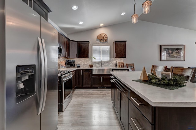 kitchen featuring a center island, light countertops, hanging light fixtures, appliances with stainless steel finishes, and a sink