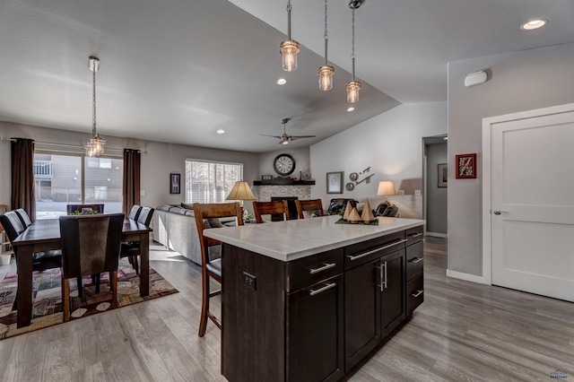 kitchen with a breakfast bar area, a kitchen island, open floor plan, light countertops, and hanging light fixtures