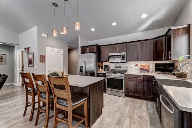 kitchen with vaulted ceiling, stainless steel appliances, light countertops, and pendant lighting