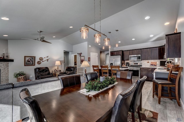 dining area featuring a fireplace, lofted ceiling, recessed lighting, light wood-style flooring, and ceiling fan