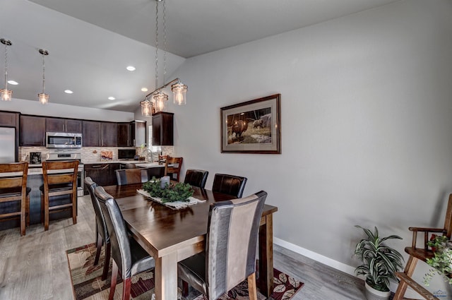 dining area featuring vaulted ceiling, recessed lighting, light wood-type flooring, and baseboards