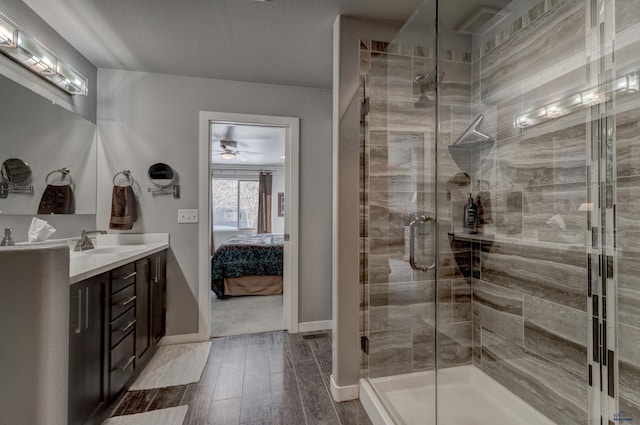 bathroom featuring ensuite bathroom, vanity, a shower stall, wood finished floors, and baseboards