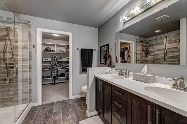 bathroom featuring a spacious closet, a sink, visible vents, and a shower stall