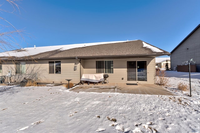 snow covered back of property featuring a patio