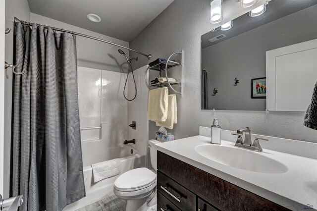 full bathroom with toilet, vanity, shower / bath combo with shower curtain, and a textured wall