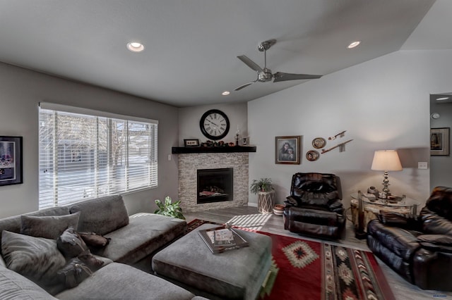 living room featuring a ceiling fan, lofted ceiling, wood finished floors, a stone fireplace, and recessed lighting