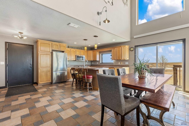 dining room with stone tile floors, recessed lighting, visible vents, a towering ceiling, and a textured ceiling