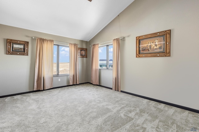 carpeted spare room featuring lofted ceiling and baseboards