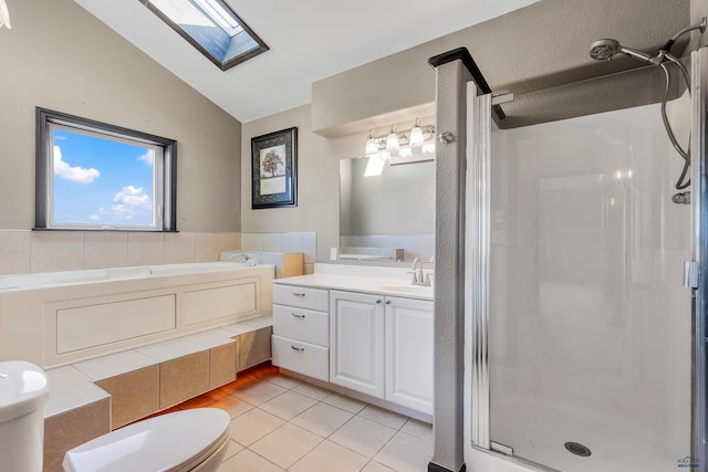 bathroom with toilet, lofted ceiling with skylight, a stall shower, vanity, and tile patterned flooring