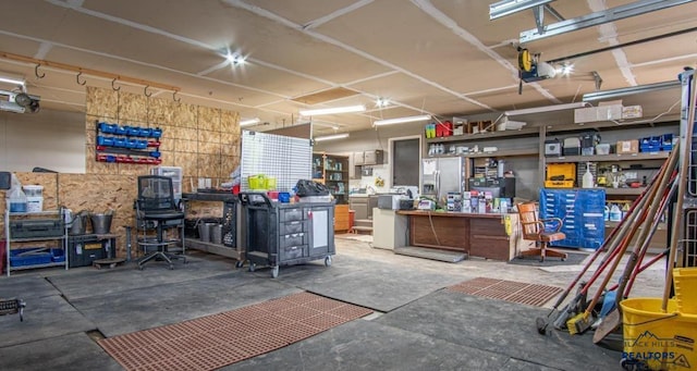 garage featuring a garage door opener, a workshop area, and stainless steel fridge with ice dispenser