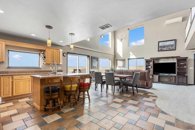 kitchen with visible vents, a breakfast bar area, open floor plan, a kitchen island with sink, and light countertops