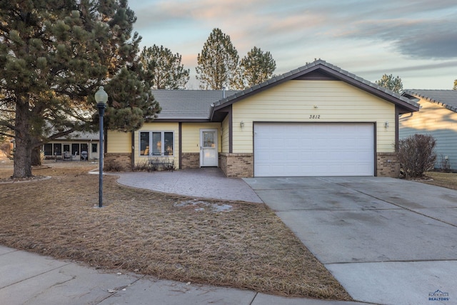 ranch-style home featuring driveway, brick siding, and an attached garage