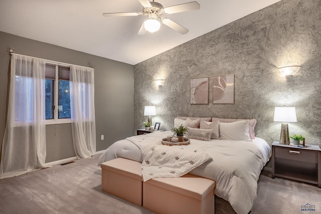 carpeted bedroom with ceiling fan, an accent wall, and vaulted ceiling