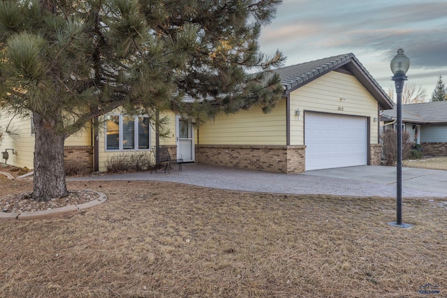 view of front facade with driveway, brick siding, and an attached garage