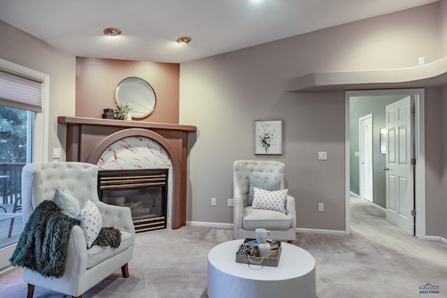 living area featuring a high end fireplace, light carpet, and baseboards