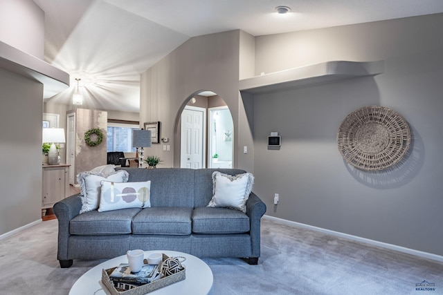 living area featuring carpet, arched walkways, vaulted ceiling, and baseboards