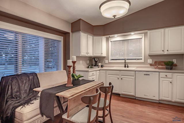 kitchen with dishwasher, light countertops, a sink, and white cabinetry