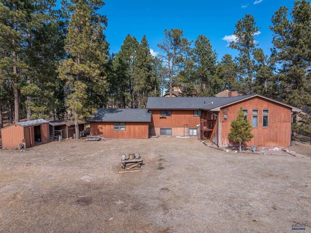 rear view of house featuring a chimney and an outdoor structure