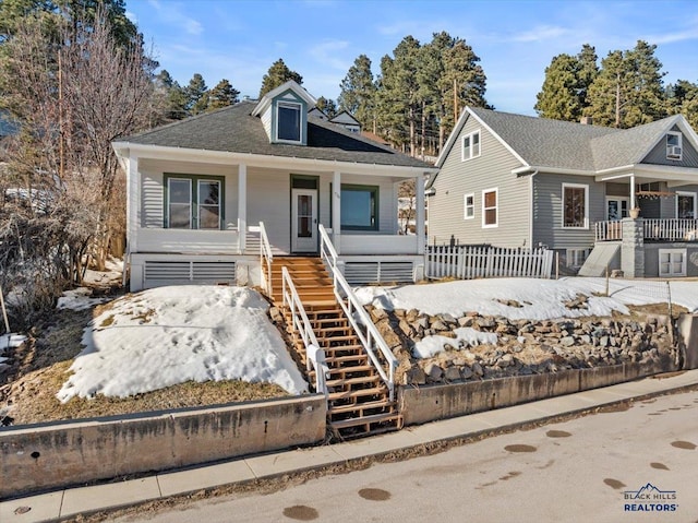 bungalow featuring covered porch, fence, and stairway