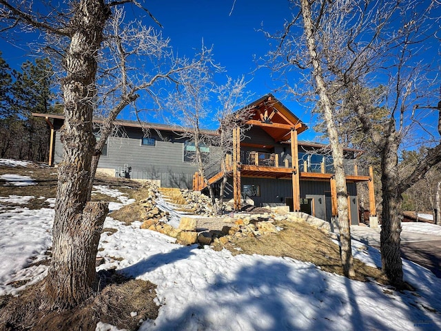 snow covered house with stairs and a wooden deck