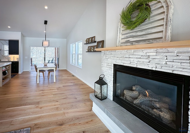 20216 Ponderosa Dr, Whitewood, SD 57793 - living room with a stone fireplace, light wood-style floors, baseboards, and high vaulted ceiling