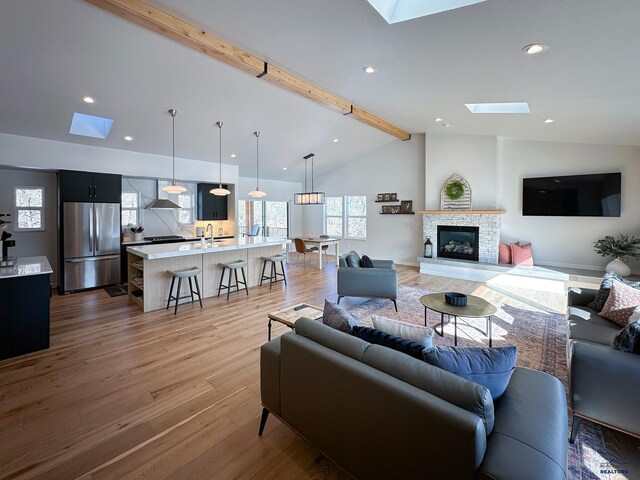 20216 Ponderosa Dr, Whitewood, SD 57793 - living room featuring a skylight, light wood-type flooring, a stone fireplace, and recessed lighting