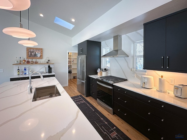 20216 Ponderosa Dr, Whitewood, SD 57793 - kitchen featuring wall chimney exhaust hood, dark cabinetry, a sink, appliances with stainless steel finishes, and a skylight