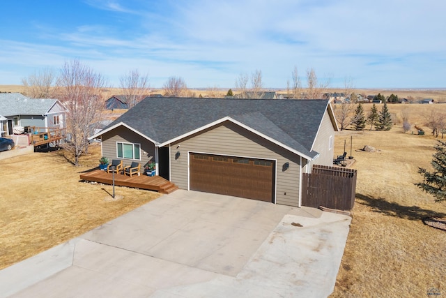 view of front facade featuring a deck, driveway, a shingled roof, and a garage