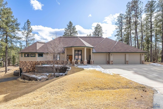 ranch-style house featuring stone siding, roof with shingles, an attached garage, and driveway