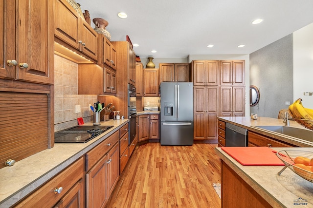 kitchen featuring stainless steel appliances, brown cabinetry, light wood-style floors, and tasteful backsplash