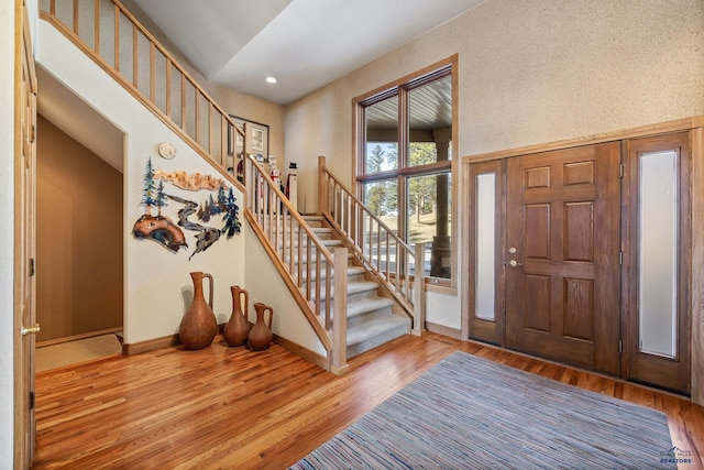 entrance foyer featuring lofted ceiling, recessed lighting, wood finished floors, baseboards, and stairway