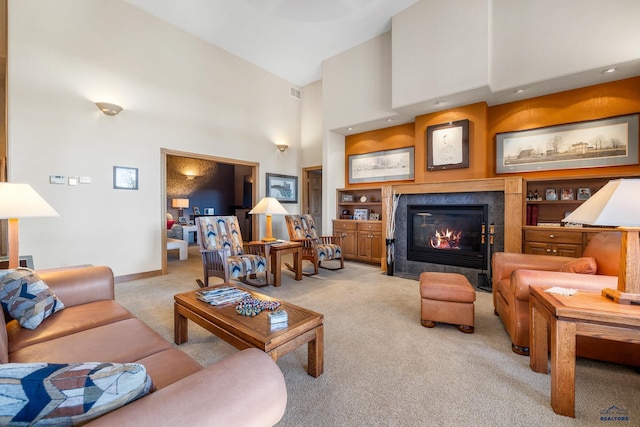 carpeted living room with visible vents, baseboards, a towering ceiling, and a tiled fireplace