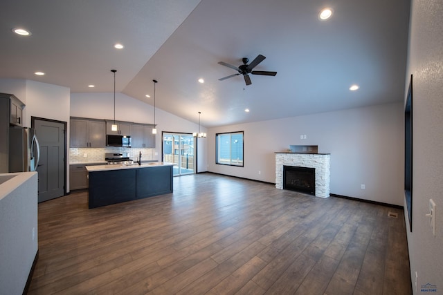 kitchen featuring open floor plan, light countertops, appliances with stainless steel finishes, and dark wood-type flooring