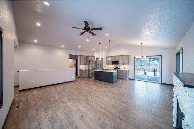 kitchen with visible vents, open floor plan, a kitchen island with sink, stainless steel appliances, and light countertops