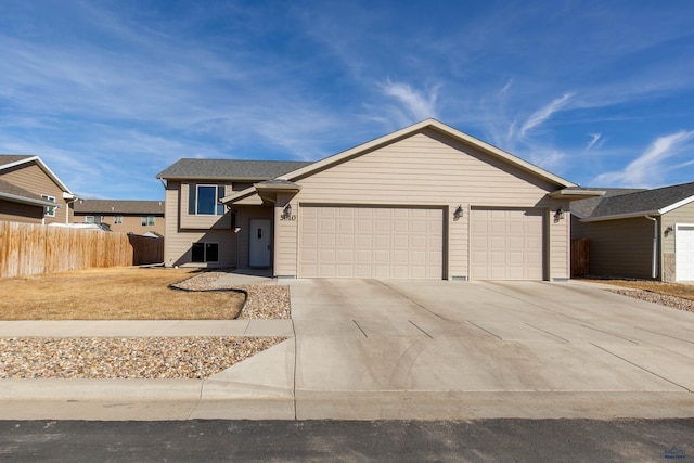 view of front facade featuring driveway, an attached garage, and fence