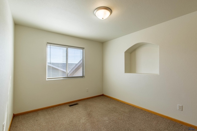 carpeted spare room with visible vents and baseboards