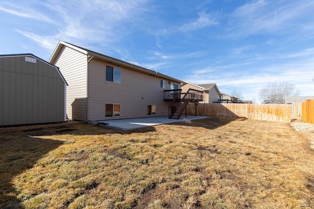 rear view of property with an outbuilding, fence, stairs, a storage unit, and a patio area