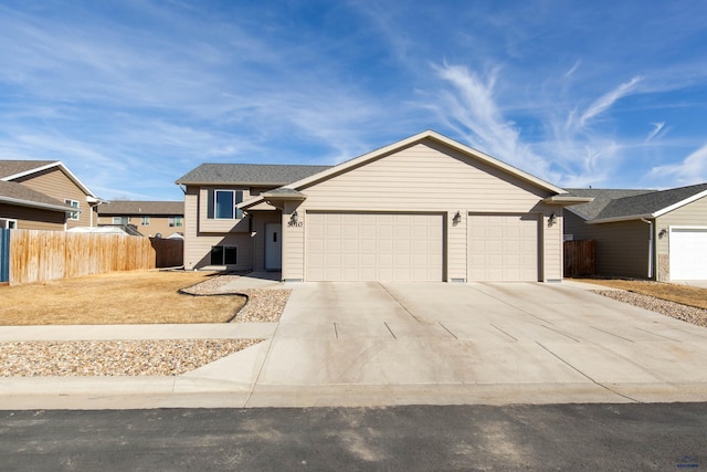 view of front of property featuring concrete driveway, an attached garage, and fence