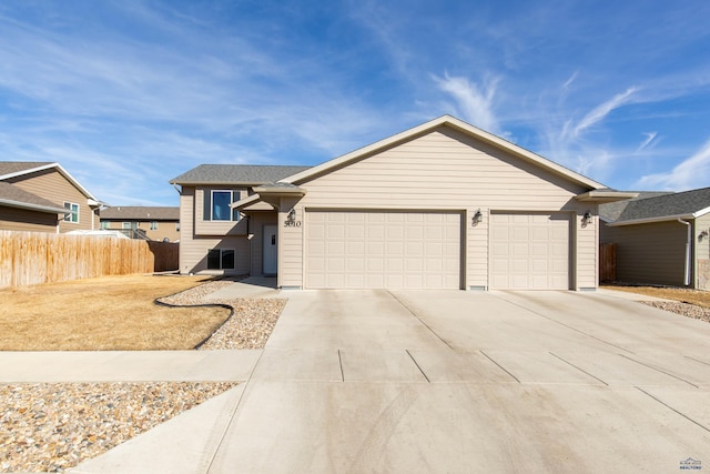 view of front of property featuring concrete driveway, fence, and an attached garage