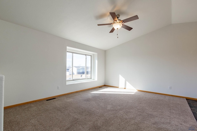 spare room with baseboards, visible vents, a ceiling fan, vaulted ceiling, and dark carpet