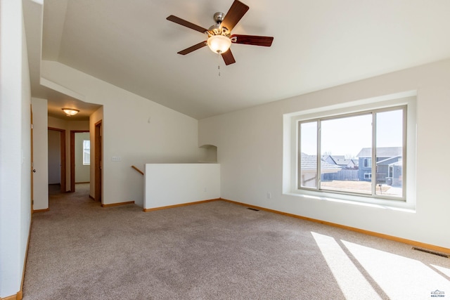 empty room featuring lofted ceiling, visible vents, light carpet, and baseboards