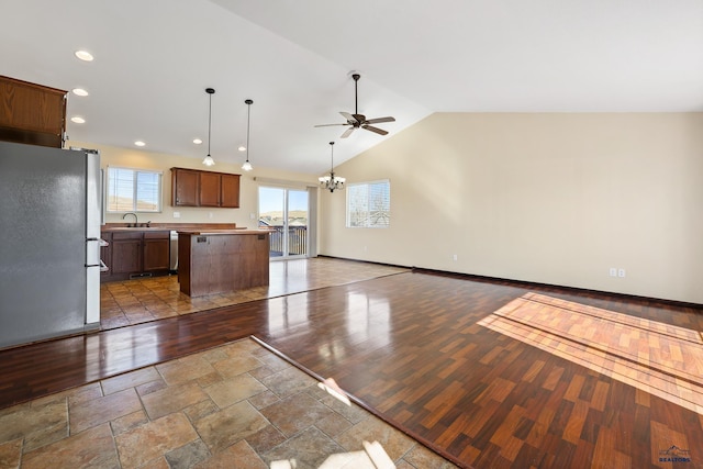 kitchen featuring stainless steel appliances, wood finished floors, open floor plan, vaulted ceiling, and a center island