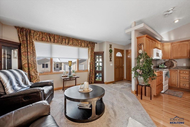 living area with lofted ceiling, light wood finished floors, and baseboards