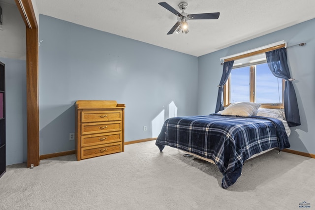 bedroom with carpet, a textured ceiling, baseboards, and a ceiling fan