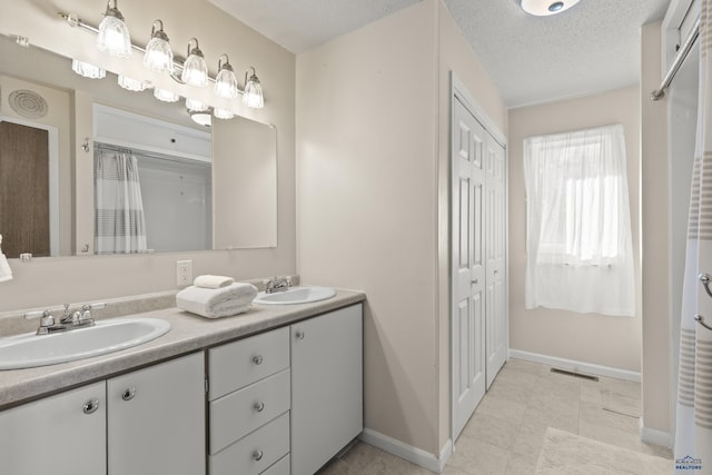 full bathroom with a textured ceiling, double vanity, a sink, and visible vents