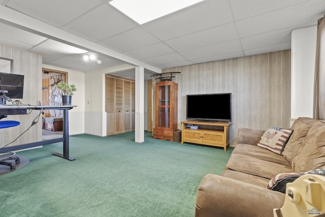 living area featuring a paneled ceiling, wood walls, and carpet