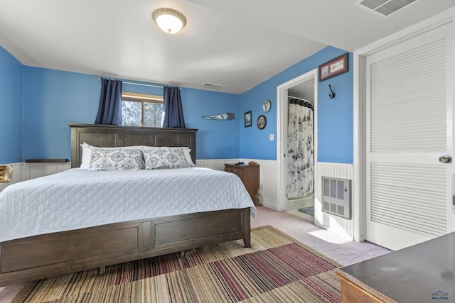 carpeted bedroom featuring wainscoting, visible vents, and heating unit