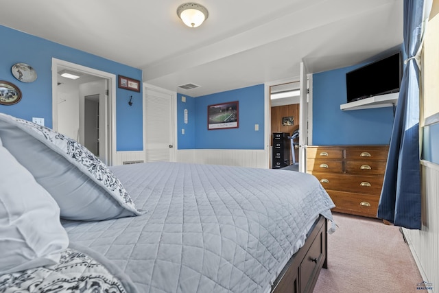 carpeted bedroom featuring a wainscoted wall and visible vents